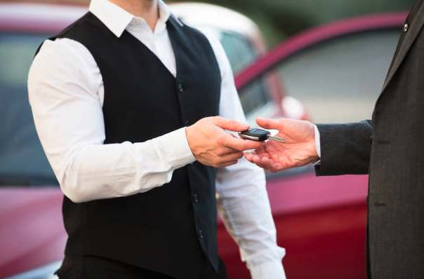A parking valet hands a car key over to its owner.